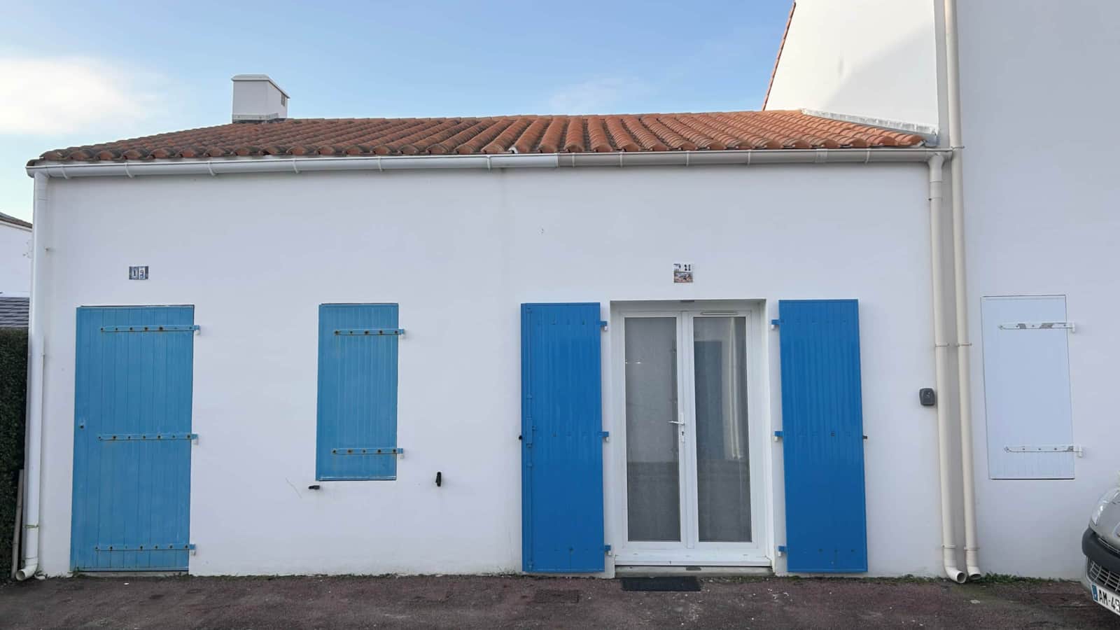 Façade blanche aux volets bleus de la maison